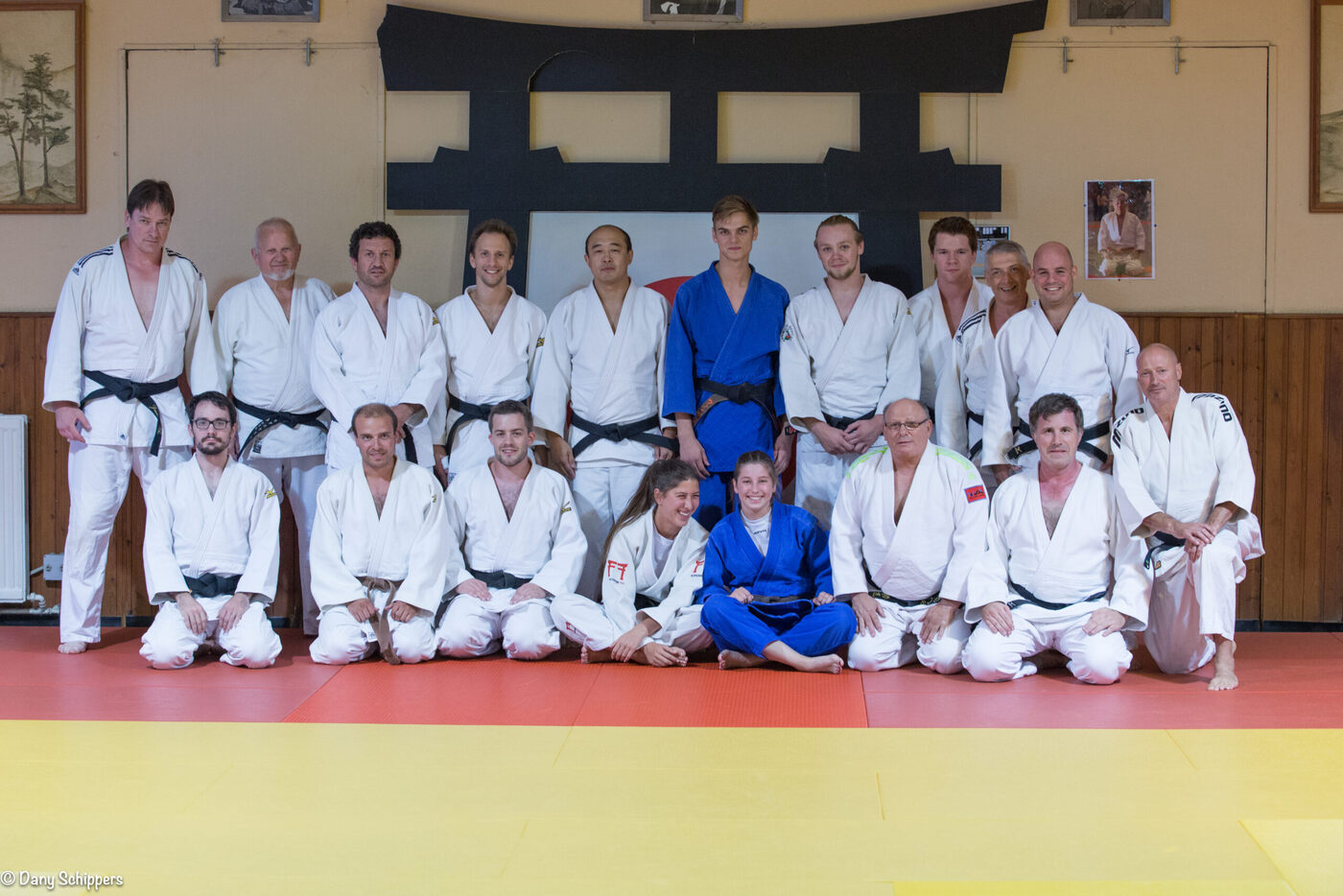 Groupe de judokas de tous âges, souriants, réunis sur le tatami